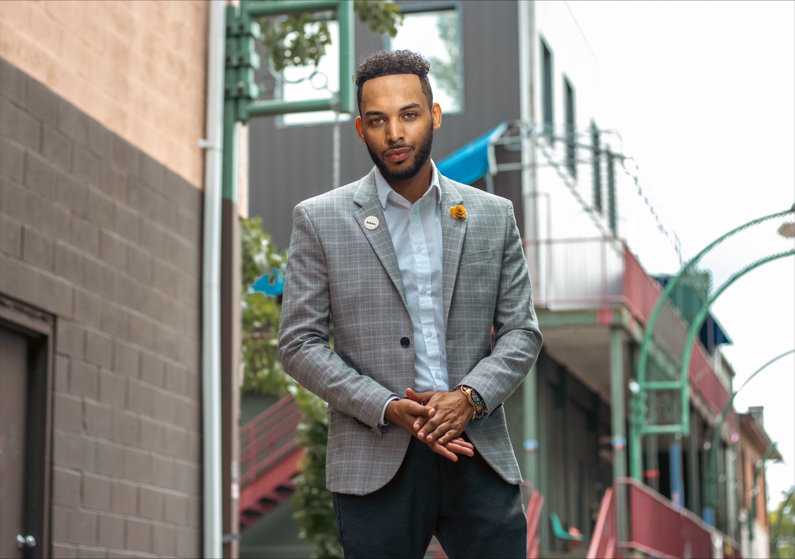 Tyler Logan, a consultant working with the Flinn Foundation, standing outdoors in an urban setting wearing a gray plaid blazer and white shirt.